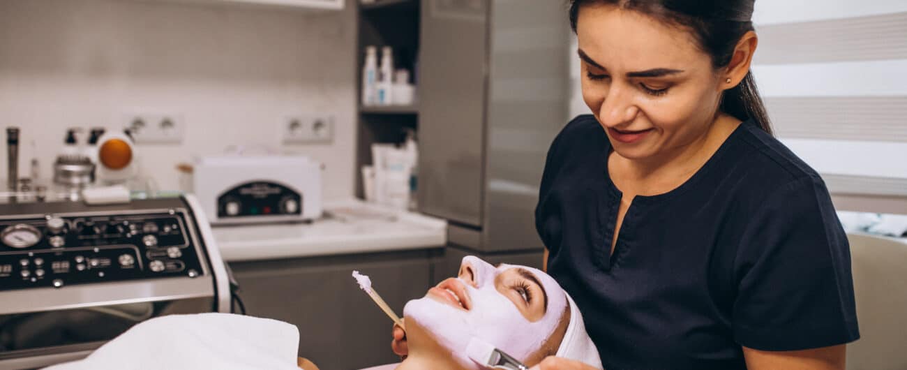 Cosmetologist applying mask on a face of client in a beauty salon