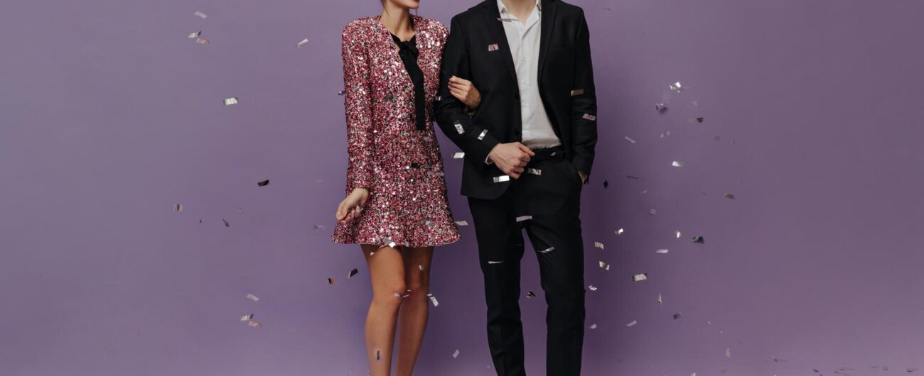 fulllength-photo-elegant-young-couple-evening-outfits-smiling-posing-with-confetti-against-light-purple-background_197531-29323