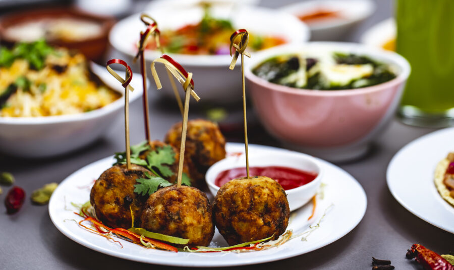 side view chicken meatballs with greens and ketchup on a plate