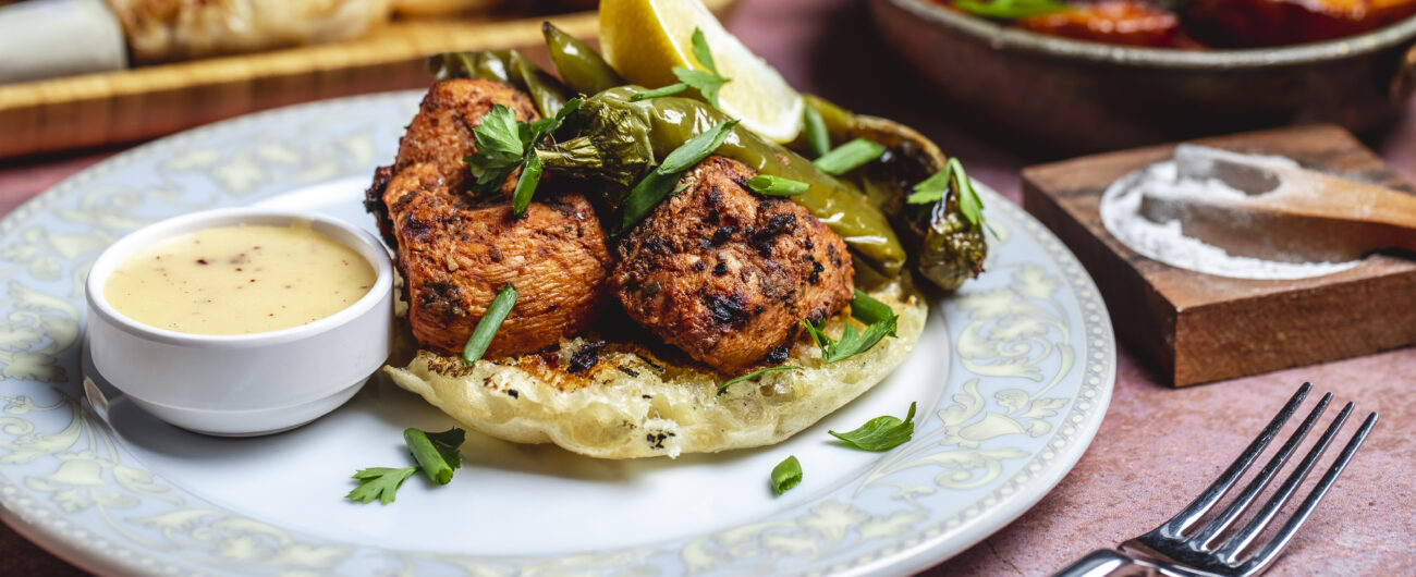 crilled chicken on bread piece greens pepper sauce spices side view