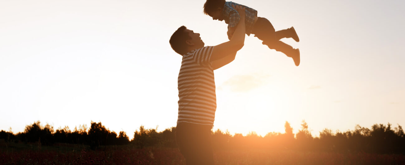 Father and son playing in the park at the sunset time. Happy family having fun outdoor