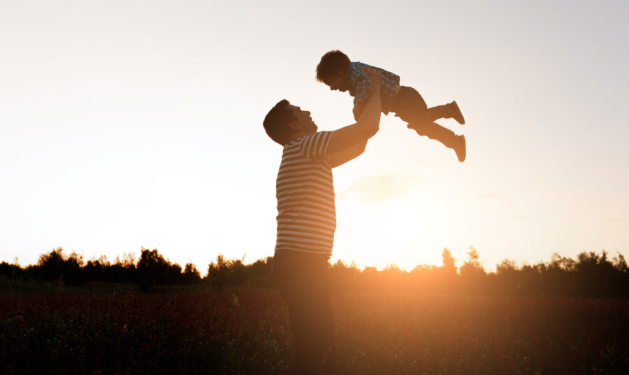 Father and son playing in the park at the sunset time. Happy family having fun outdoor